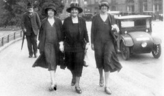 Three ladies on the town, hats and coats and a spring in their walk as they command the sidewalk.