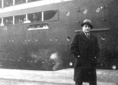 Man poses beside docked ship.