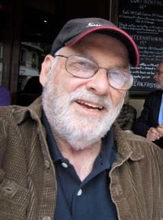 Pete Vanlaw, white beard, glasses, baseball cap, brown jacket, smiling.