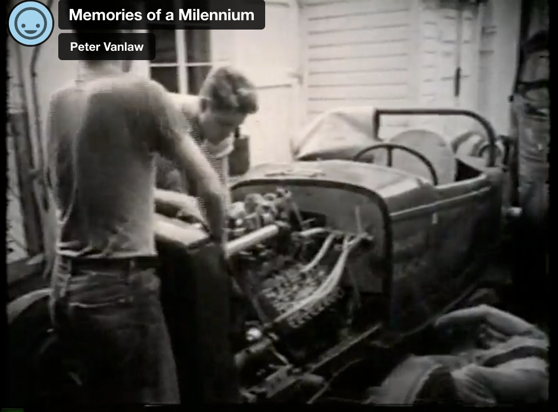 Two young men work on a stripped-down 1950s-era hot rod street racing car.